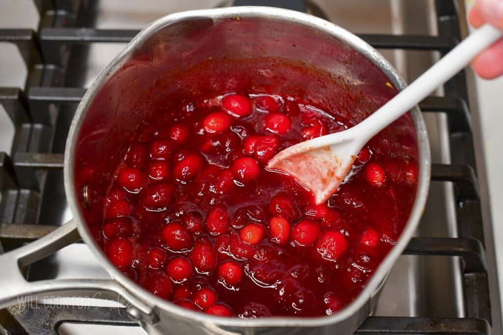 stirring the cranberry sauce in a pot.