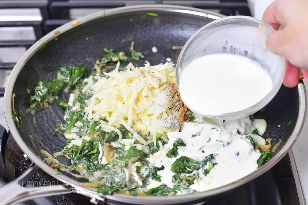 adding cream and cheese to the cooked spinach.