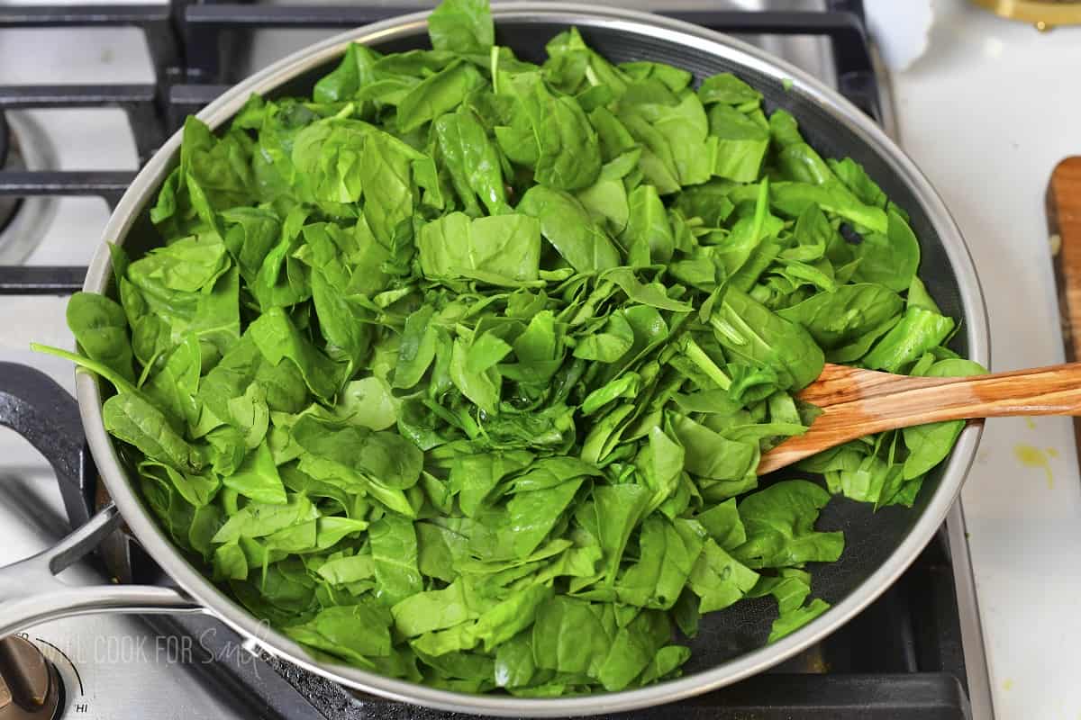adding chopped spinach to the cooking pan.