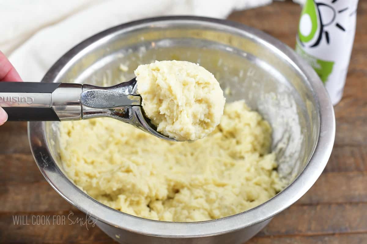 scooping out some mashed potato mixture from a bowl.