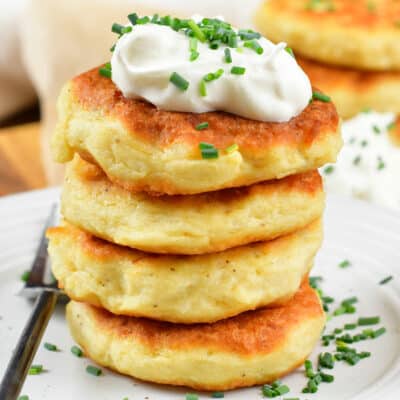 closeup of four stacked mashed potato cakes with sour cream.