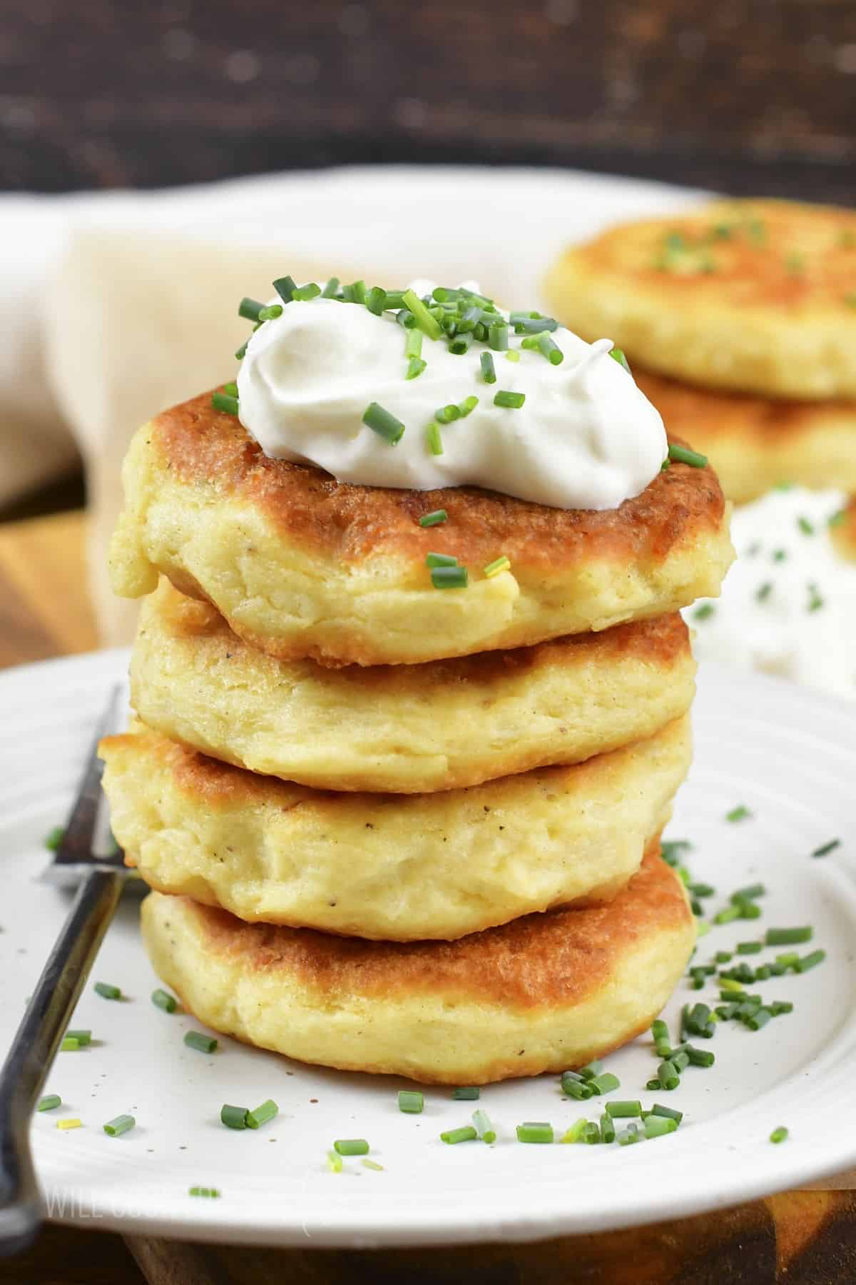 four mashed potato cakes stacked with sour cream on top.