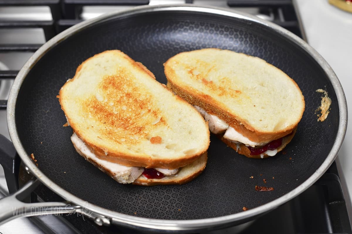 two grilled cheeses cooking in the pan.