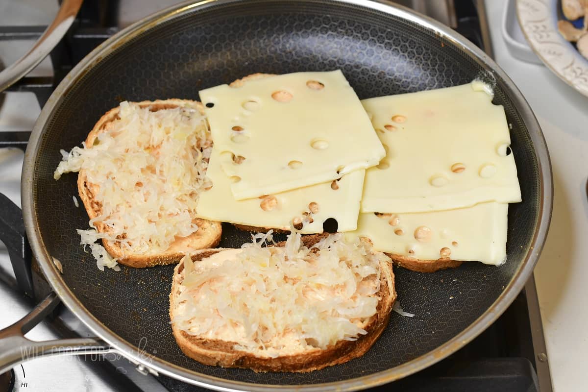 four slices of bread in the pan two with cheese and two with sauerkraut.