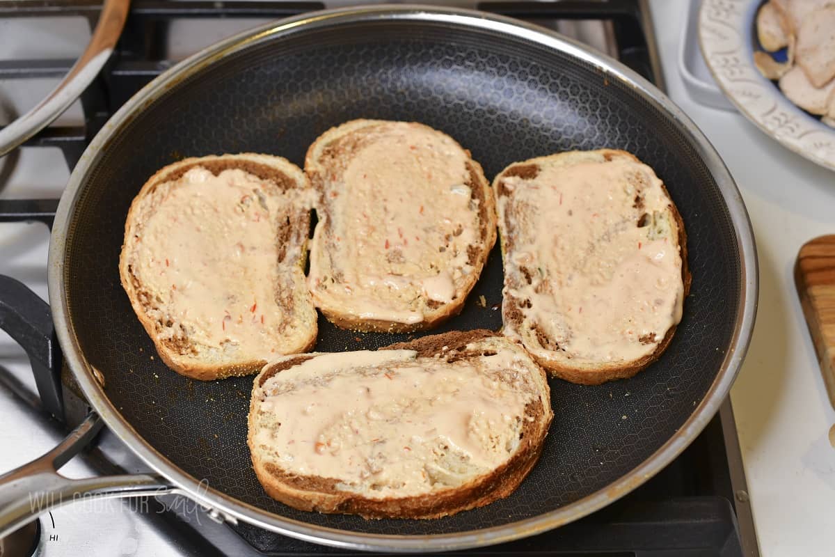 four slices of bread with 1000 island dressing in the pan.