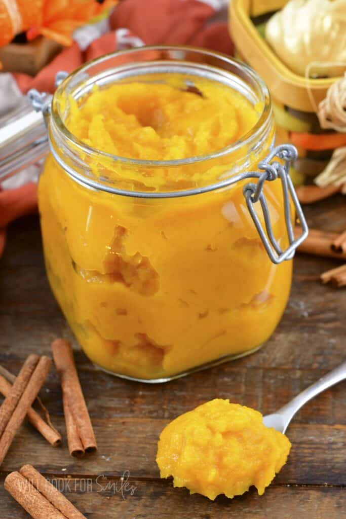 pumpkin puree in a glass jar with spoonful next to it.