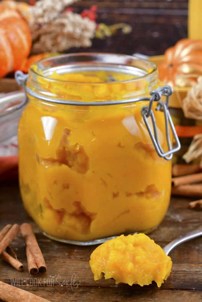 spoonful of pumpkin puree in front of the filled glass jar.