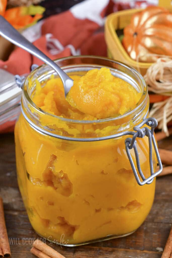 scooping out pumpkin puree from the jar with a spoon.