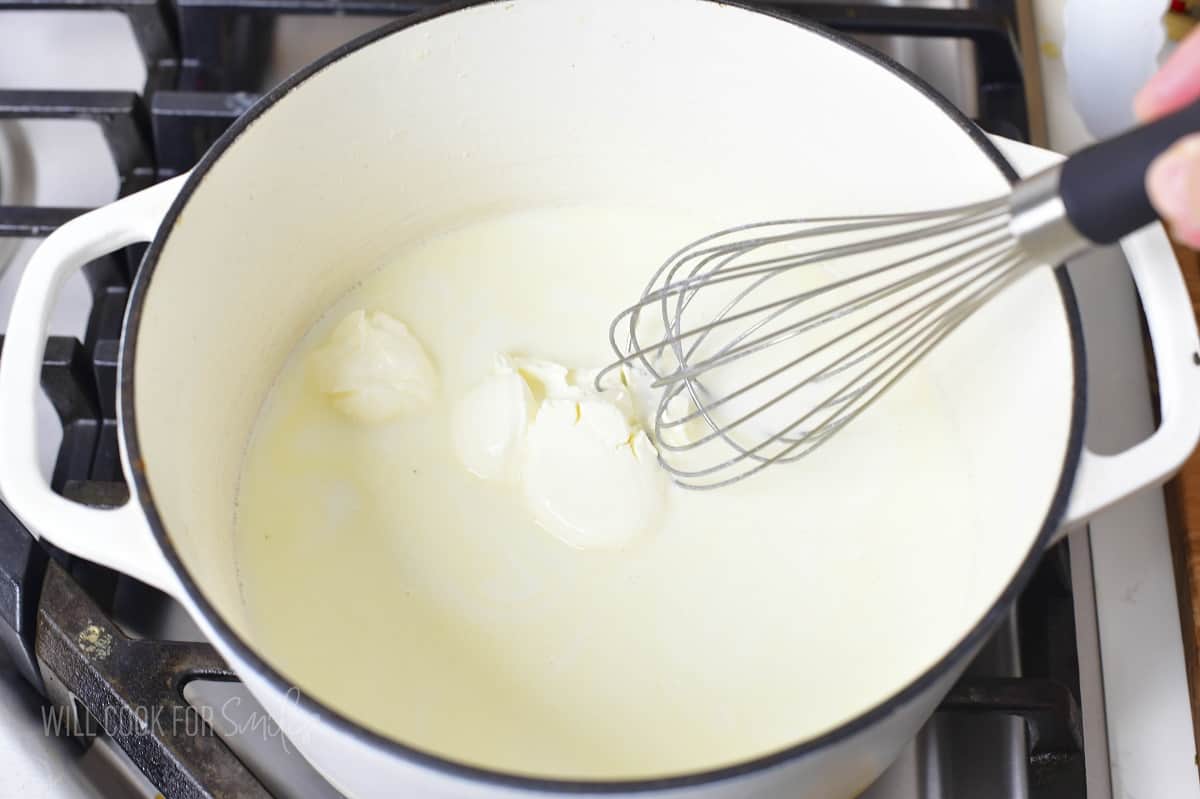 stirring cream cheese with milk in the white pot.