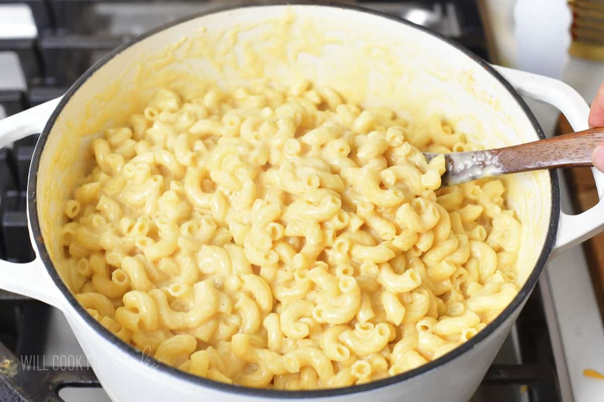 stirring macaroni with cheese sauce.