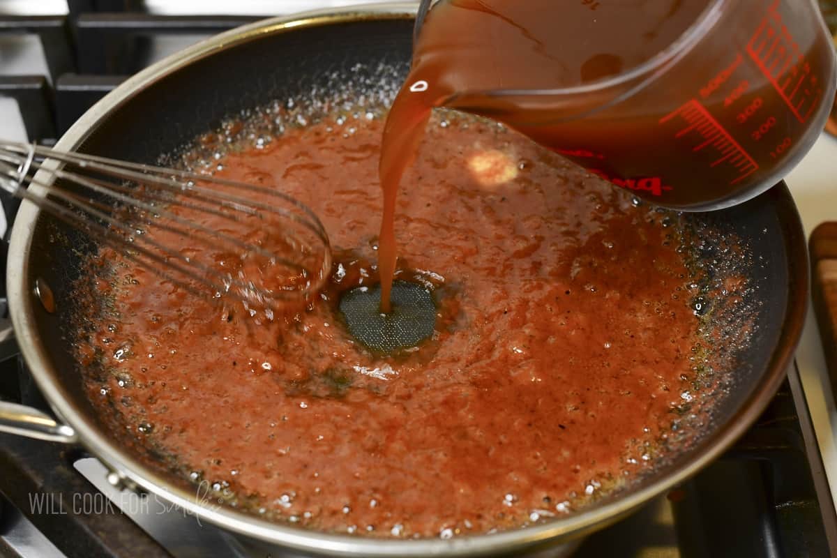 adding beef stock to the pan with thick wine mixture.