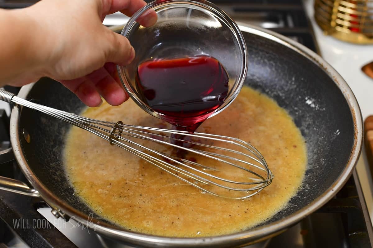 adding red wine to the flour mixture in the pan.