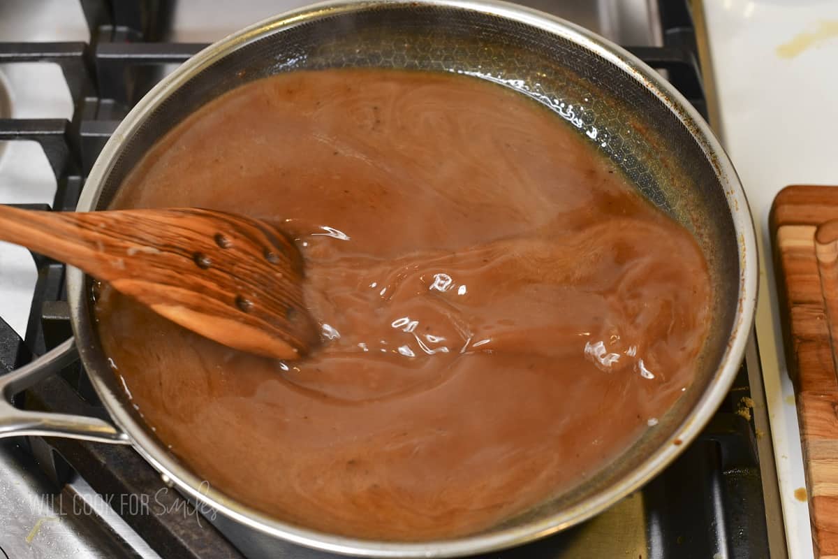 stirring au jus brown sauce in the cooking pan.