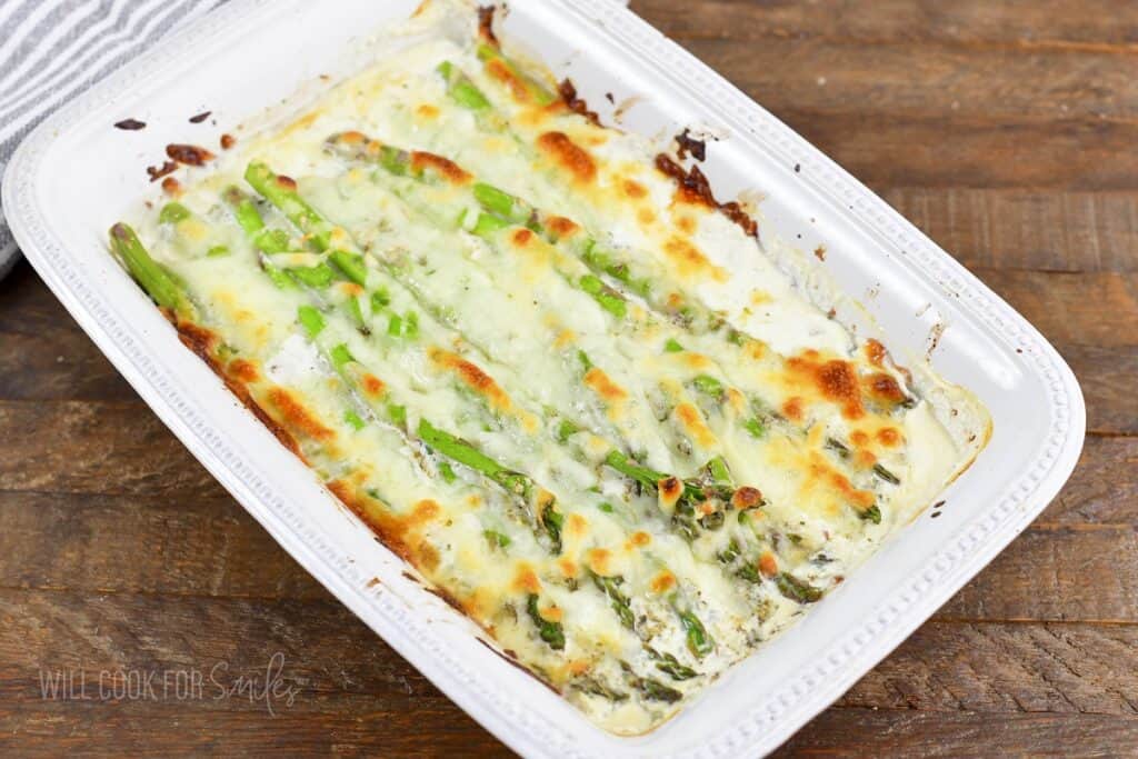 creamy baked asparagus in a white baking dish.