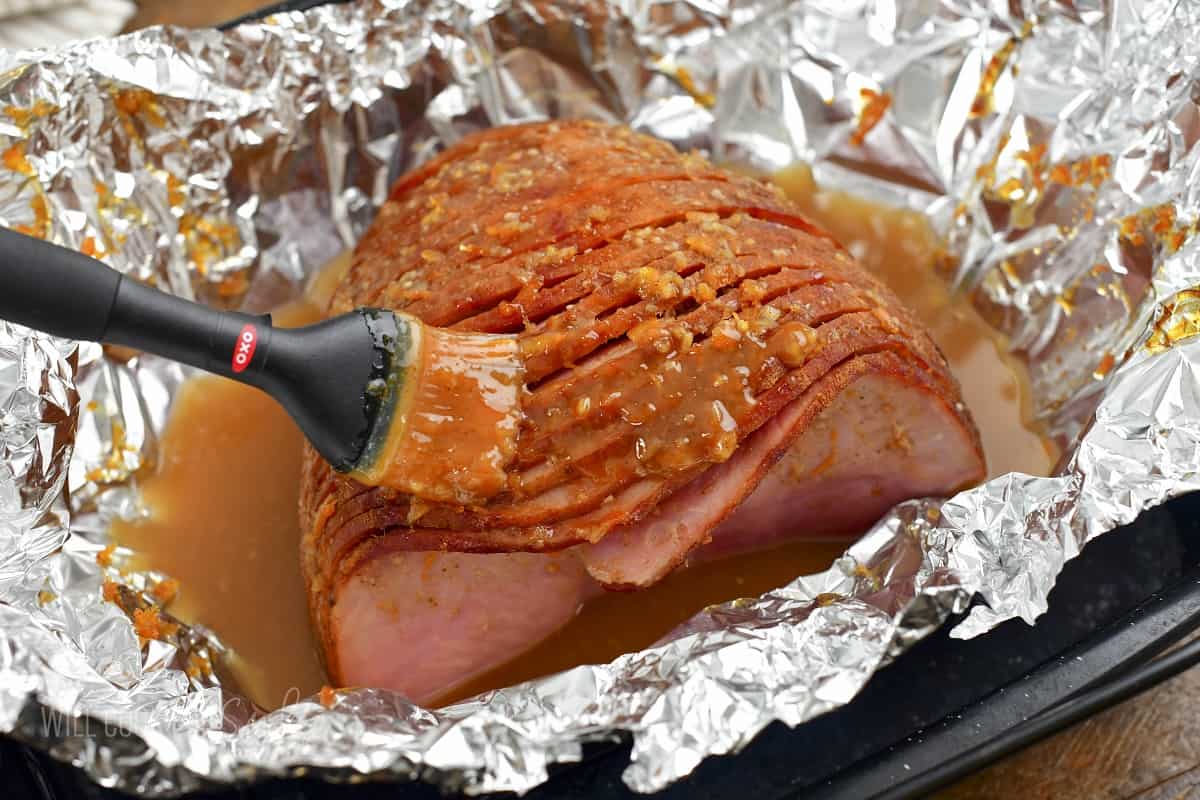 brushing second round of glaze onto baked ham.