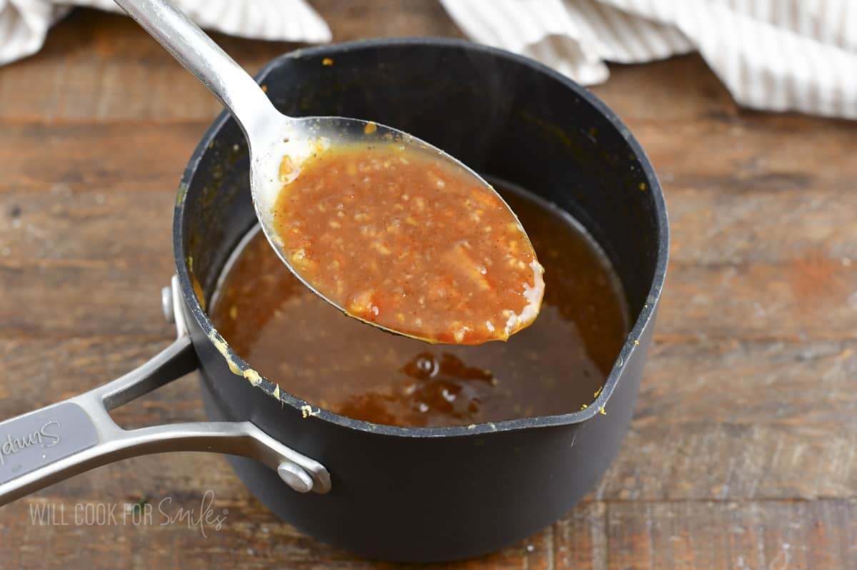scooping cooked glaze from the pot with a spoon.