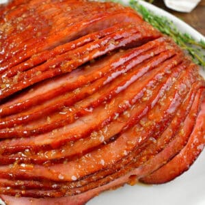 squared closeup of baked ham with orange ham glaze.