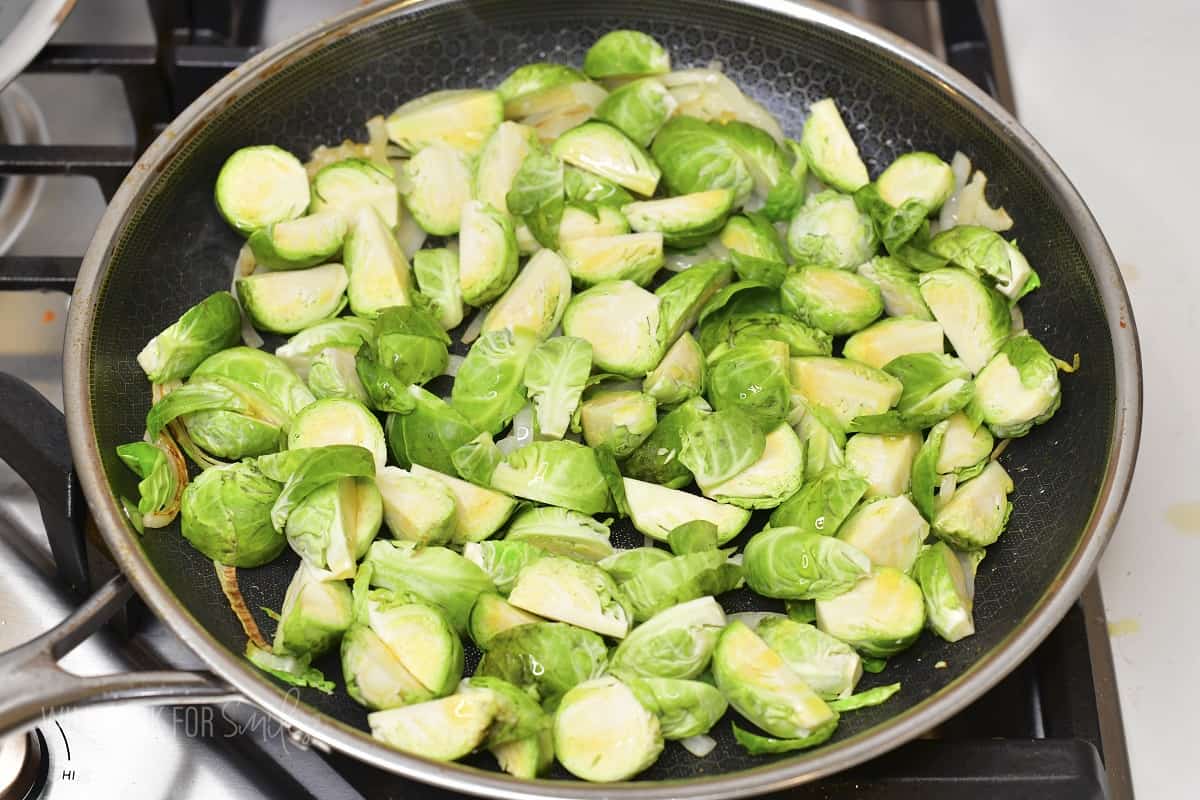 adding cut brussels to the cooking pan.
