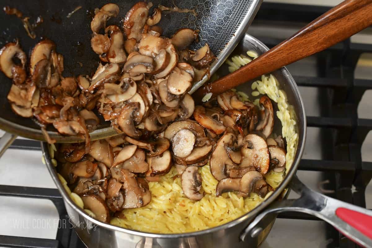 adding sautéed mushrooms to the pot with orzo.