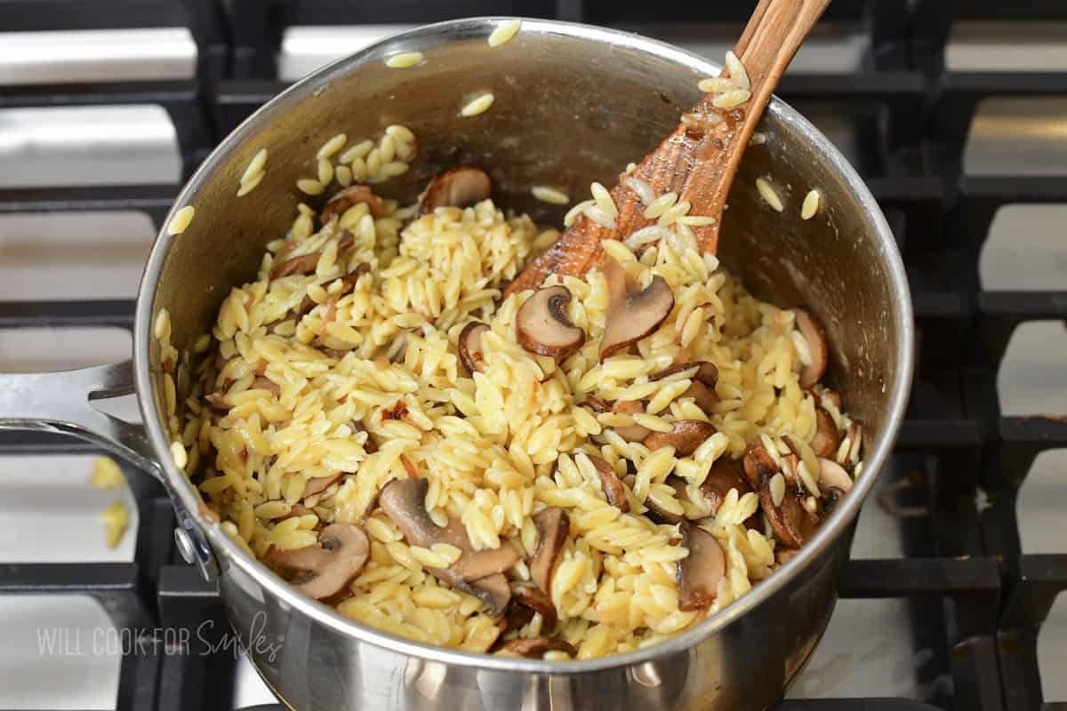 mixing mushrooms into parmesan orzo.