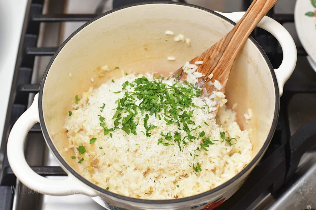 cooked creamy rice with parmesan cheese and parsley in a pot.