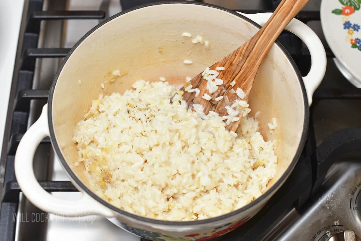 fluffing cooked rice in a pot with a wooden spatula.