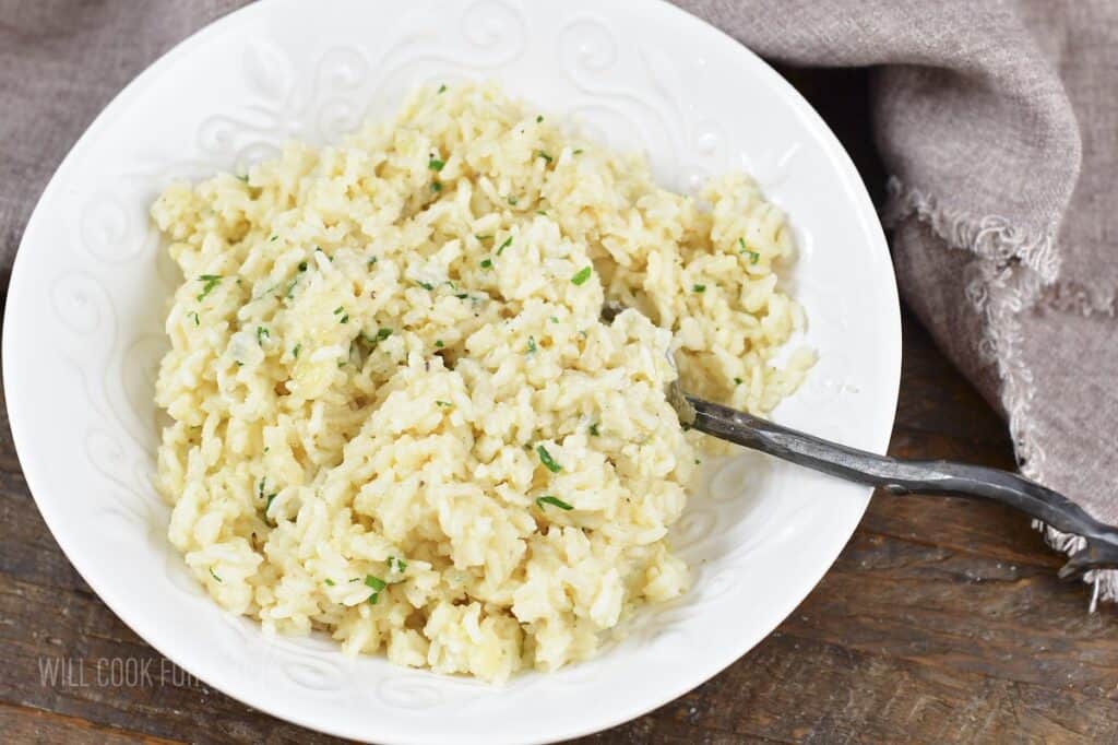 creamy parmesan rice in a bowl with a spoon.