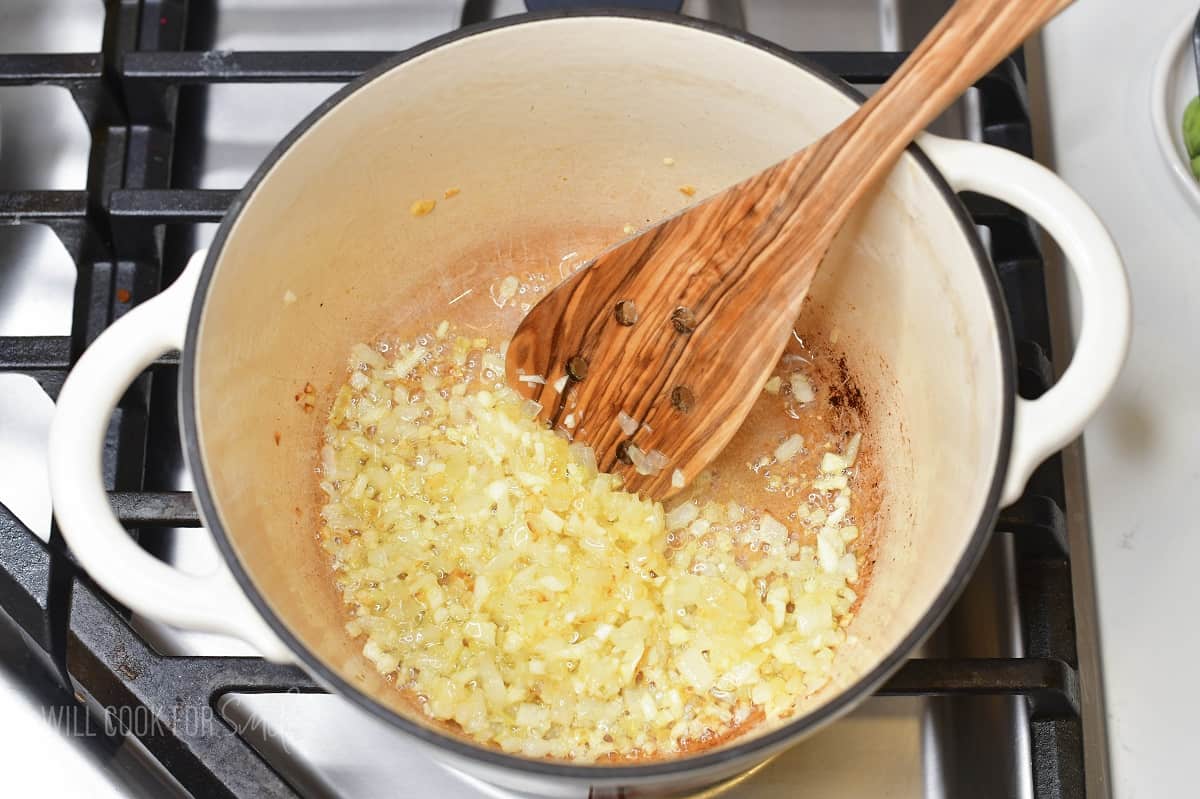 sautéing diced yellow onion in a pot.