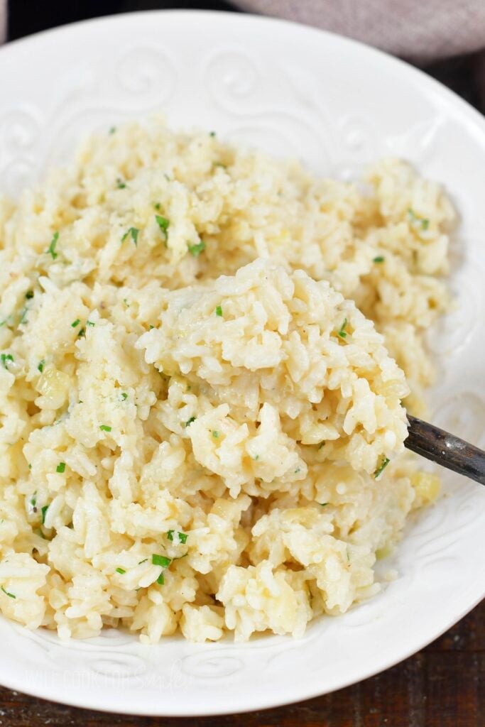 spooning out some parmesan rice from a bowl.