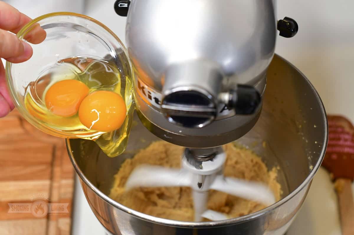 adding eggs to the cookie dough in a mixer.