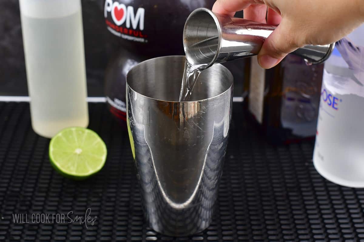 pouring Cointreau into the cocktail shaker.