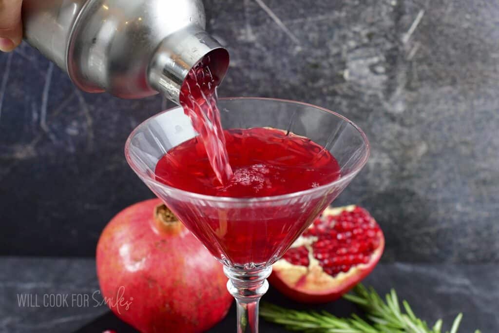 pouring in pomegranate martini into the glass.