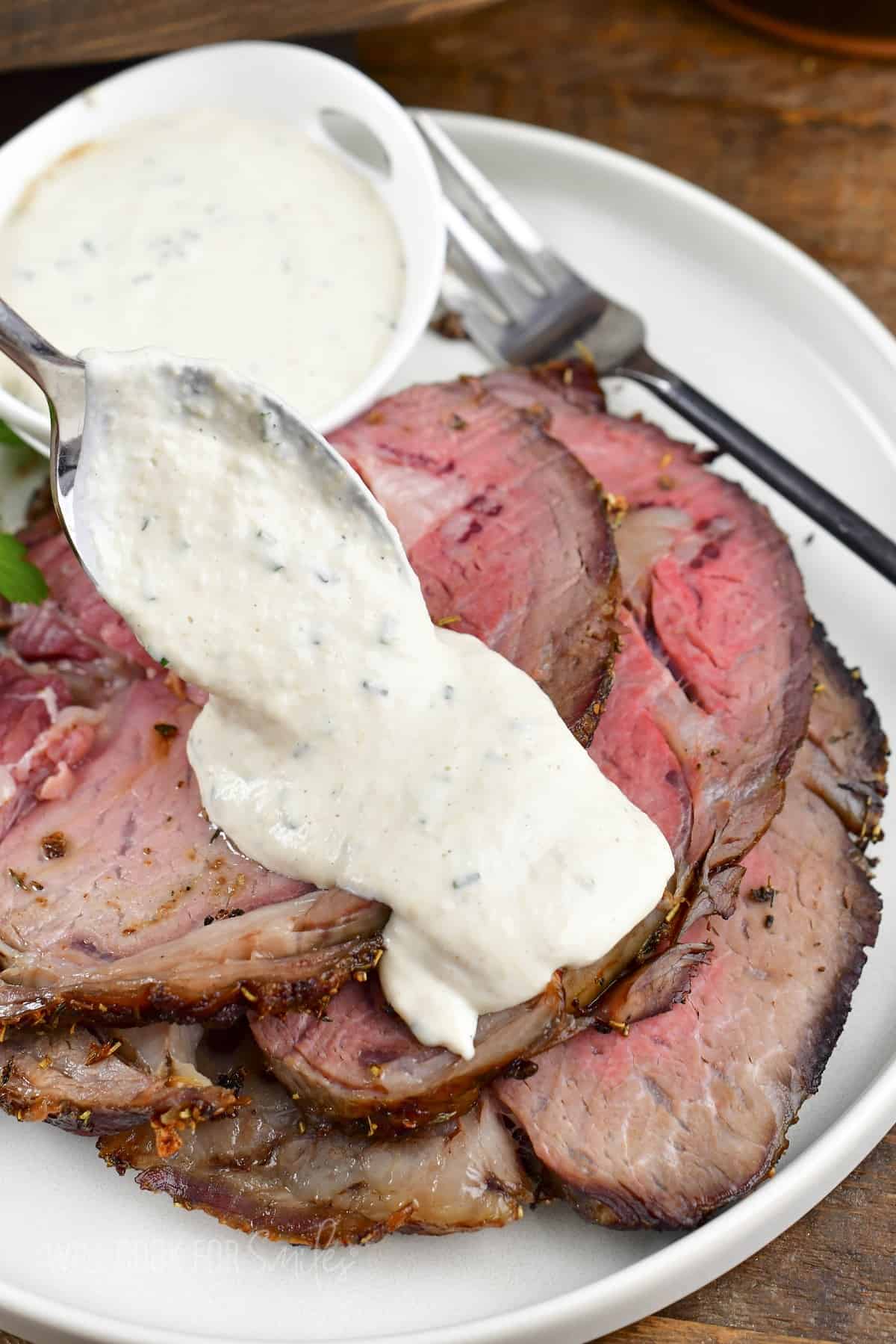 adding horseradish sauce on top of price rib slices.