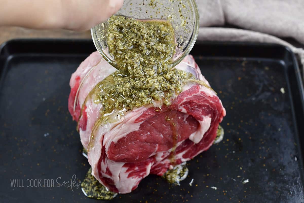 adding the seasoning mixture over tied prime rib.