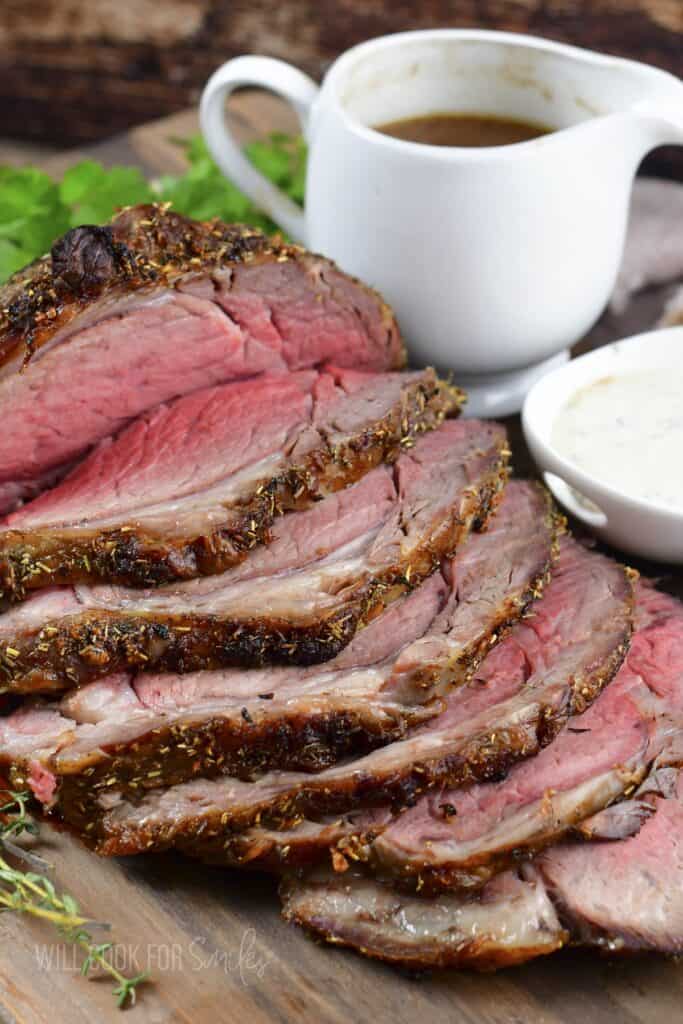 side view of sliced prime rib with sauces next to it.