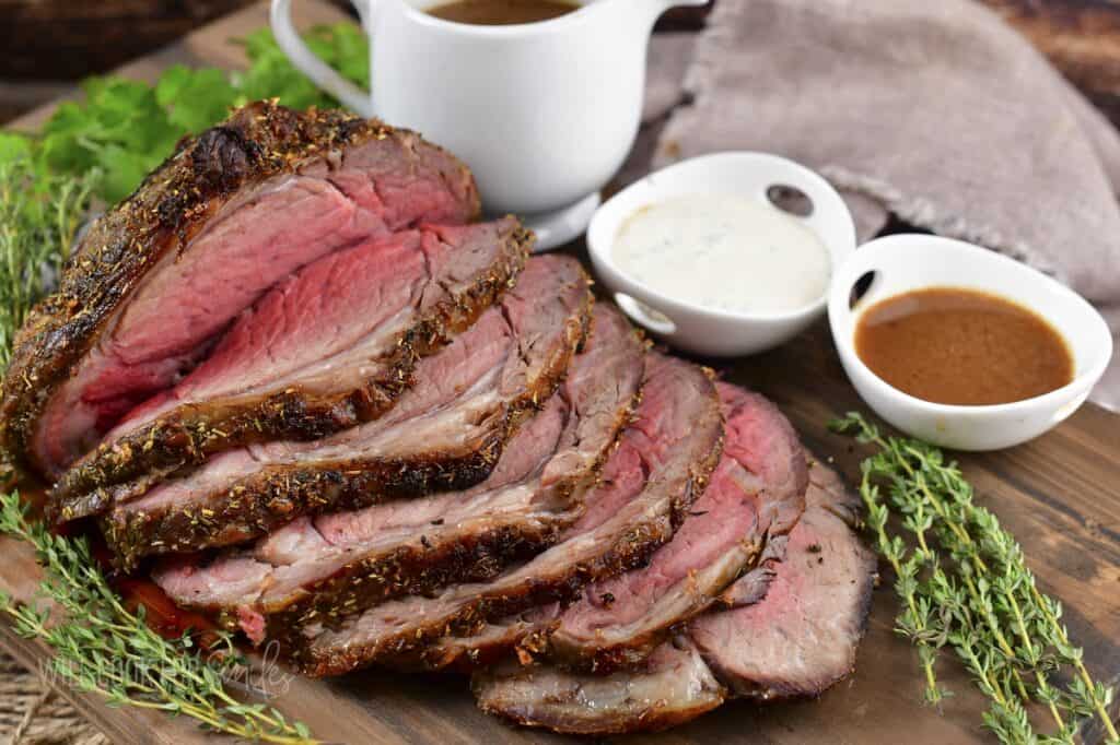 sliced prime rib on the board with au just and horsey sauce.