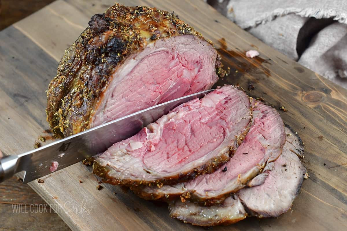 slicing prime rib roast in a cutting board.