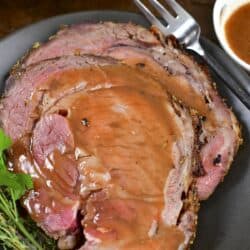 closeup of two slices of prime rib topped with au jus.