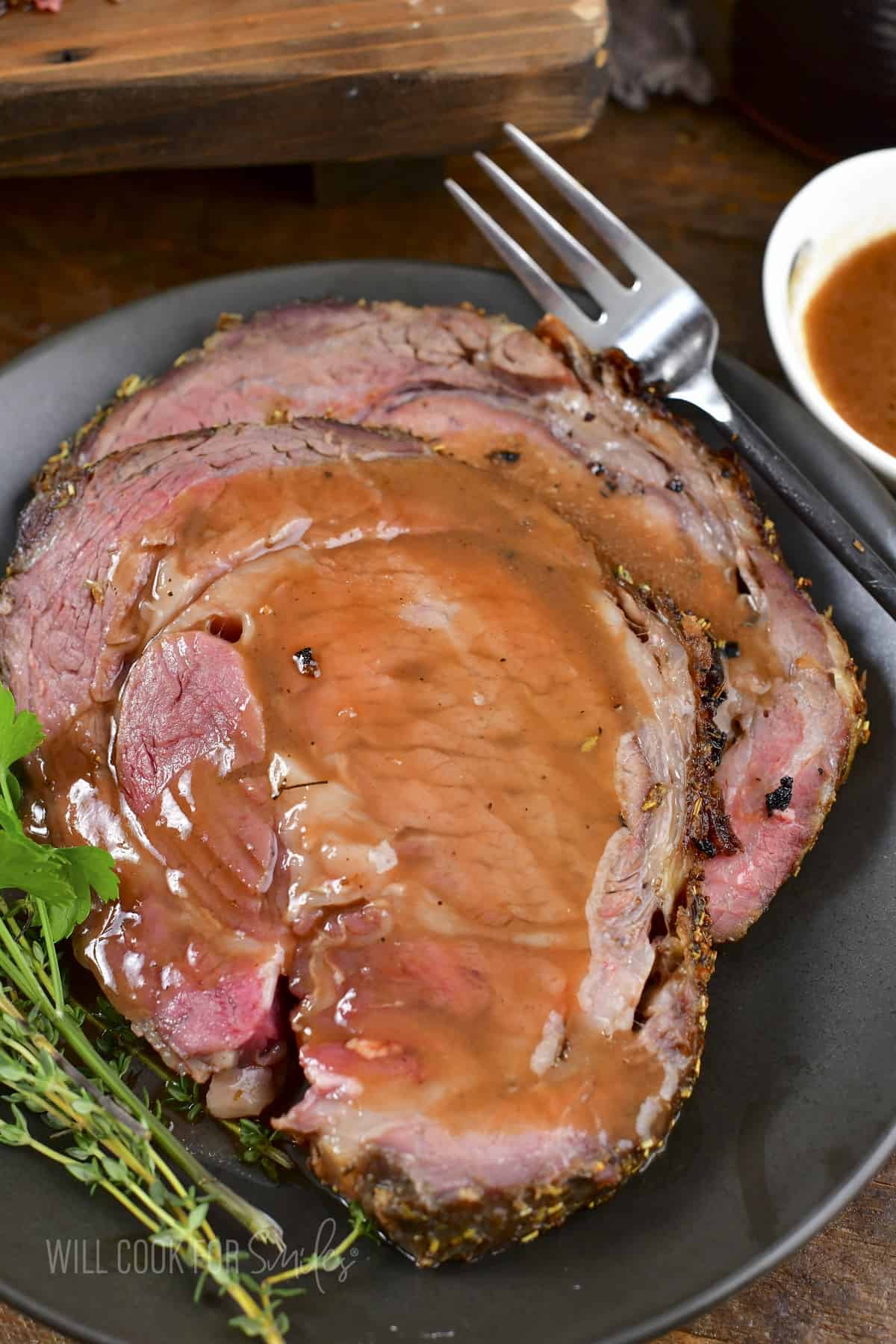 closeup of two slices of prime rib topped with au jus.