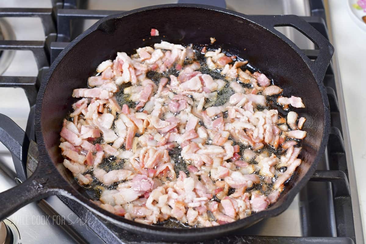 cooking bacon pieces in the skillet.