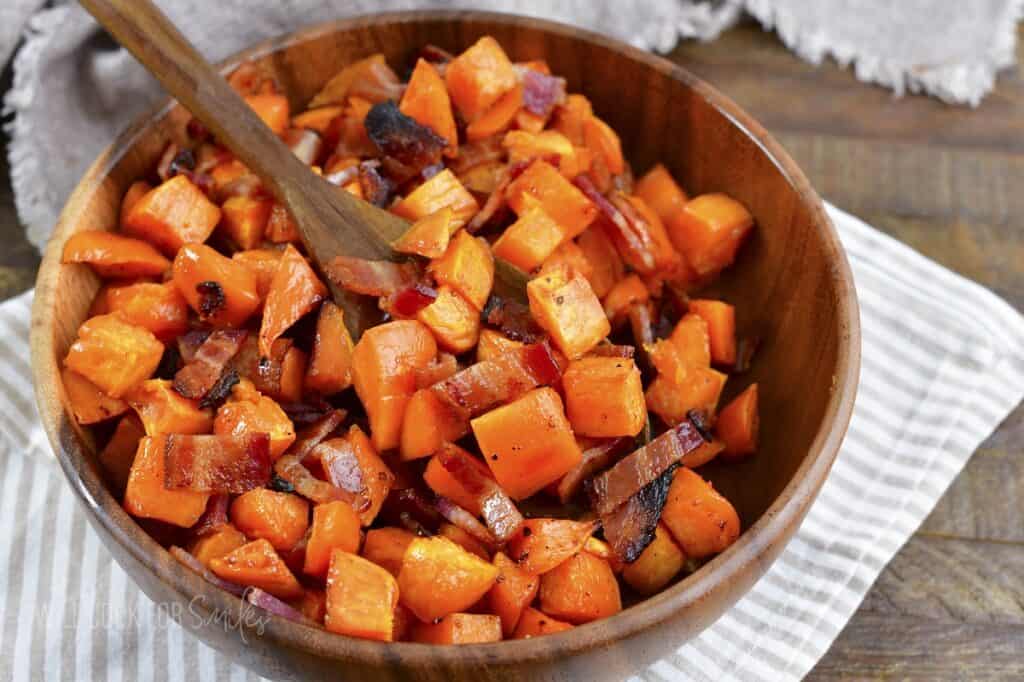 spooning out some roasted sweet potatoes from the bowl.
