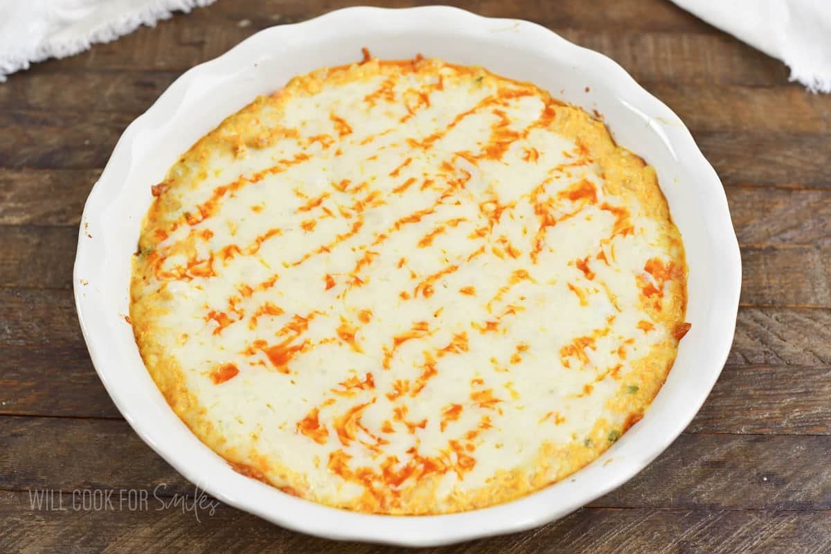 baked buffalo chicken dip in a white baking dish.