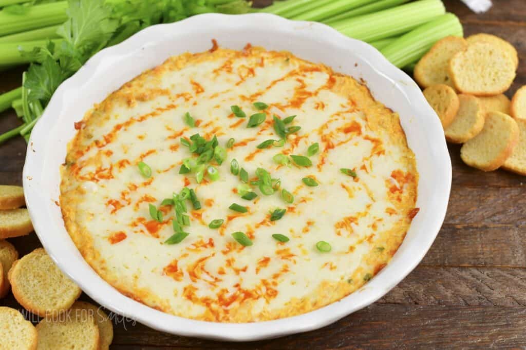 closeup of baked buffalo dip with green onions on top.