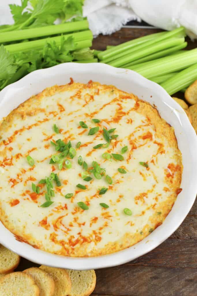 closeup of baked buffalo chicken dip with celery around.