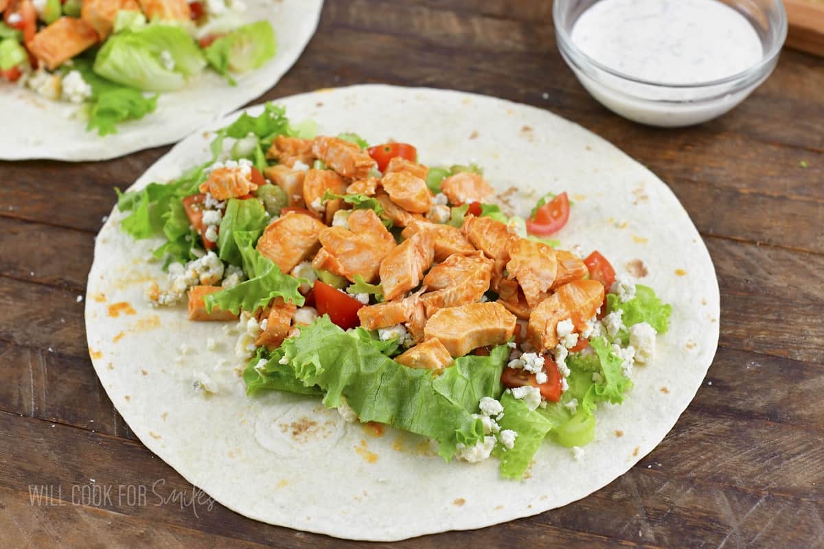 adding ingredients inside the tortilla for buffalo wrap.