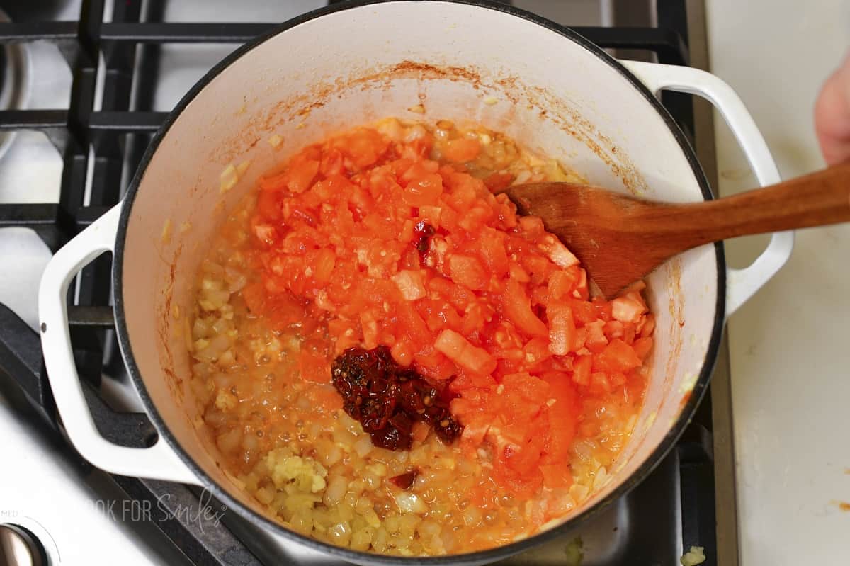 adding diced tomatoes and chili pepper to the pot.