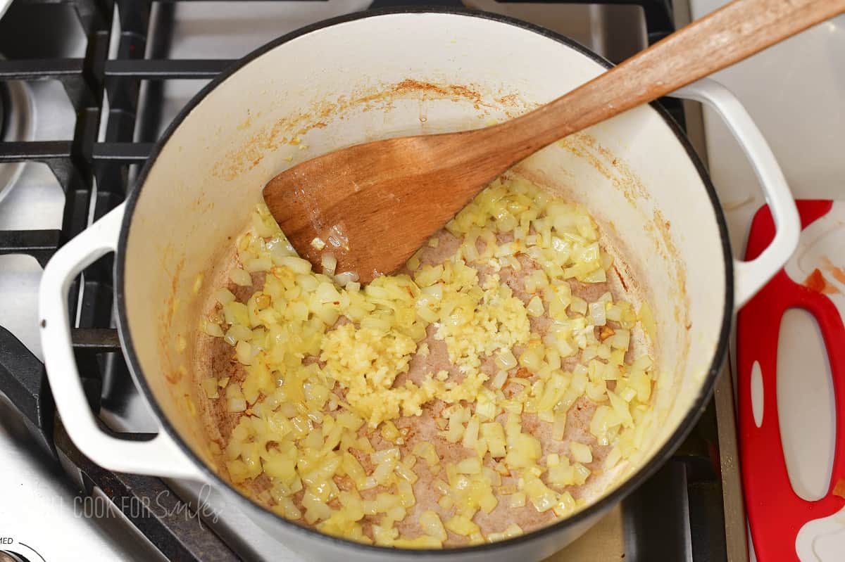 sauteeing diced onions and garlic in a pot.