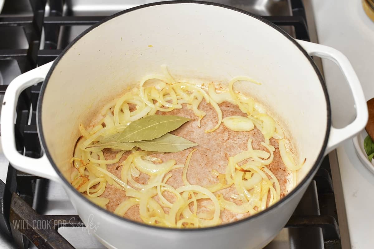 sautéing sliced onions and bay leaves in a pot.