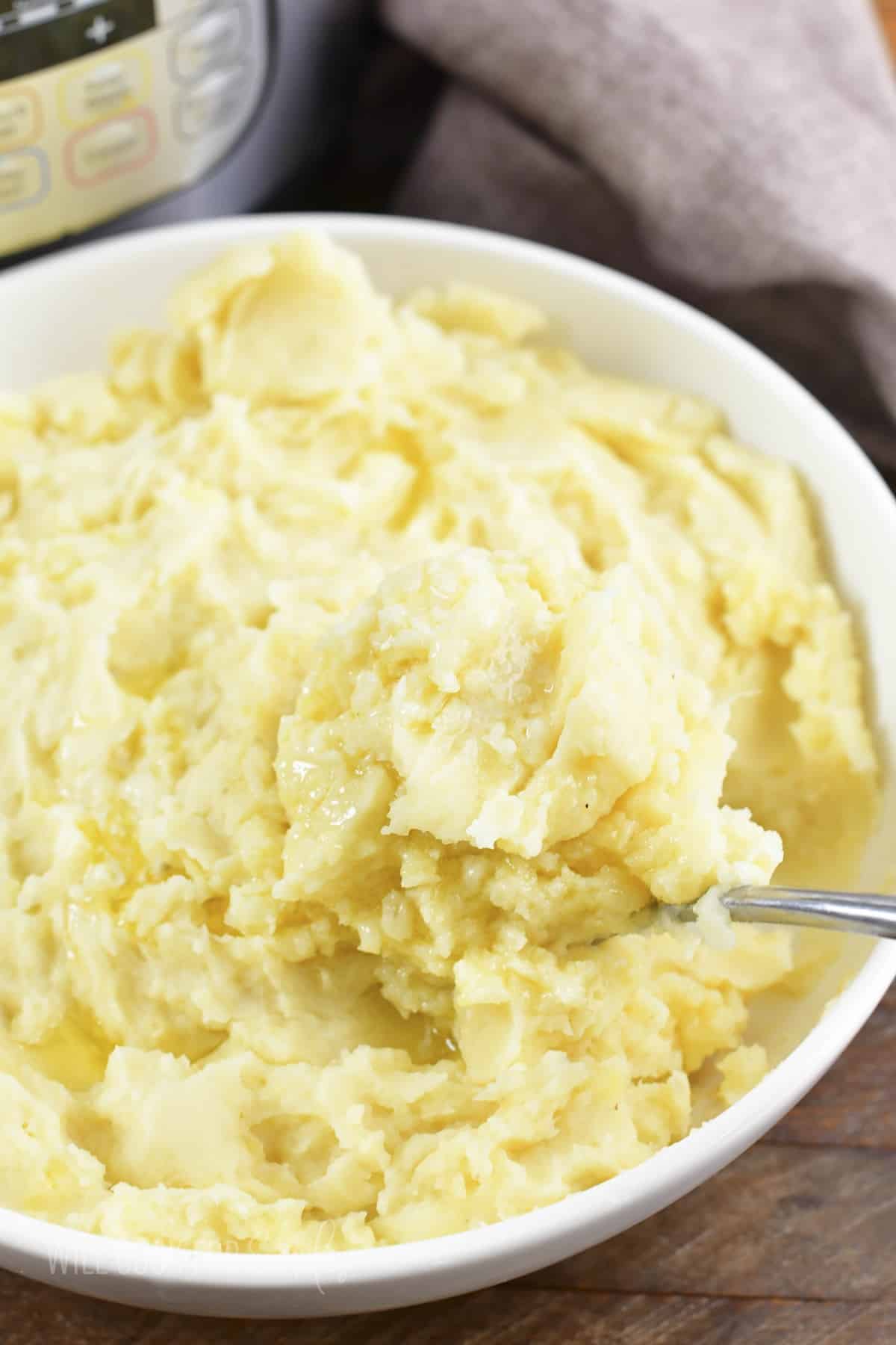 scooping out some mashed potatoes from a white bowl.