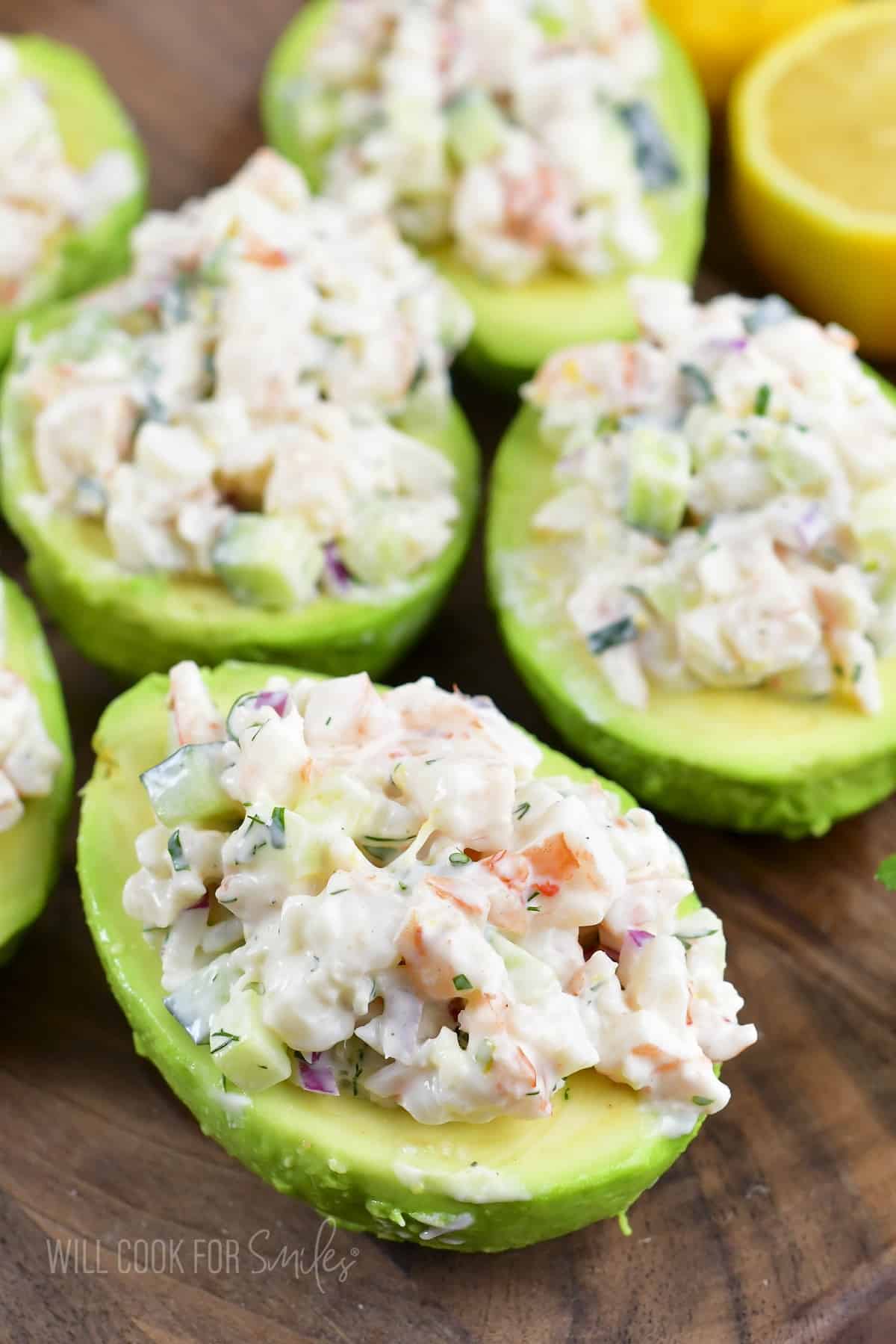 four shrimp salad stuffed avocados on the wood board.